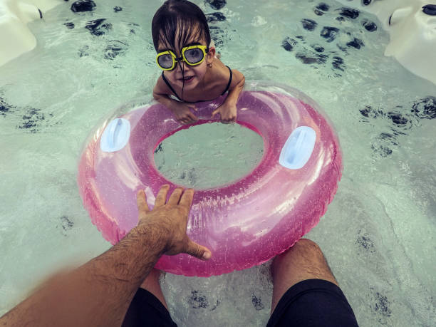 Elementary age cute girl playing in the hot tub with her father